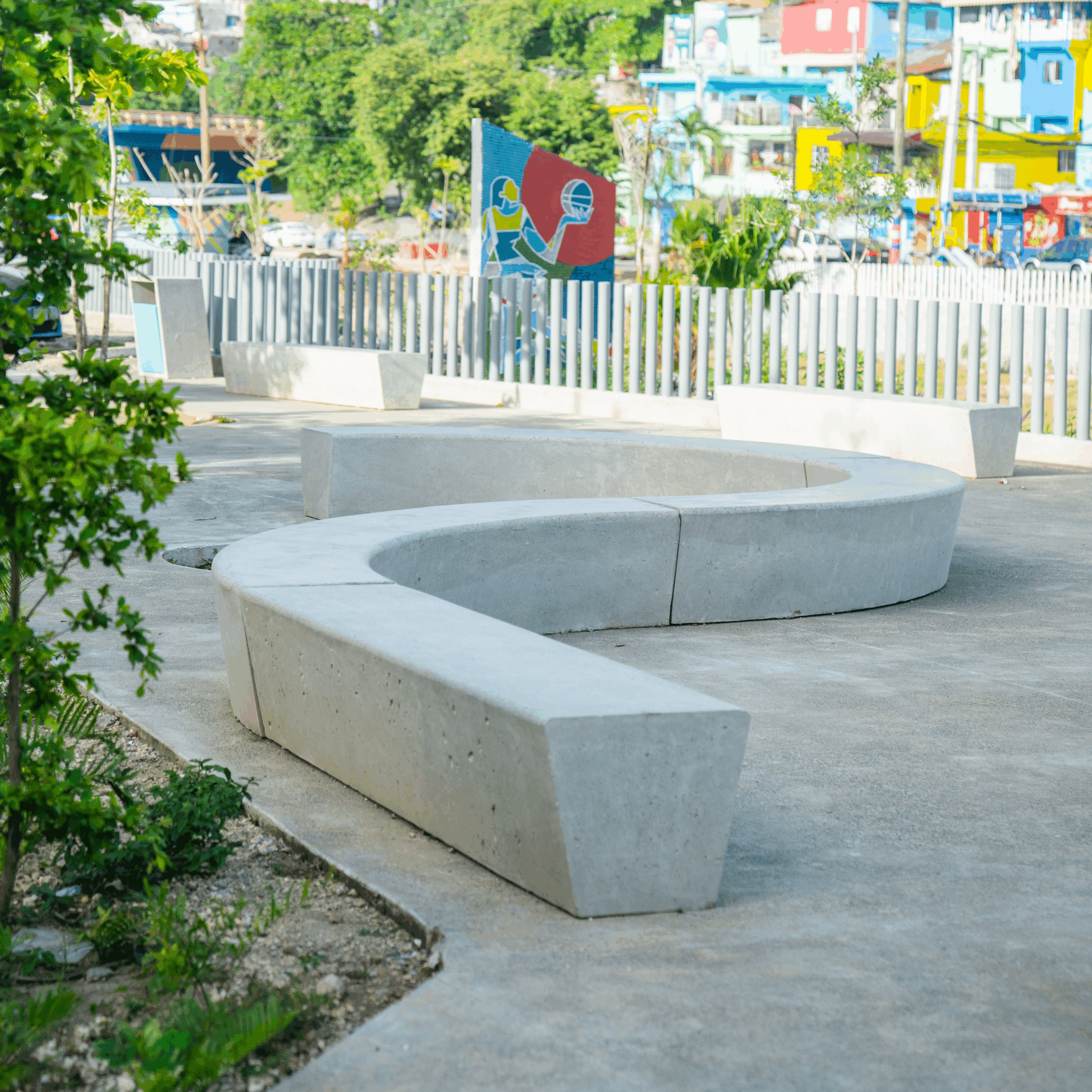 "Parque colorido con jardineras, letreros, bancos y basureros de concreto diseñados por Gola Urbano en comunidad integrada"